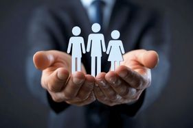 a person in a suit holding a paper cutout of a family